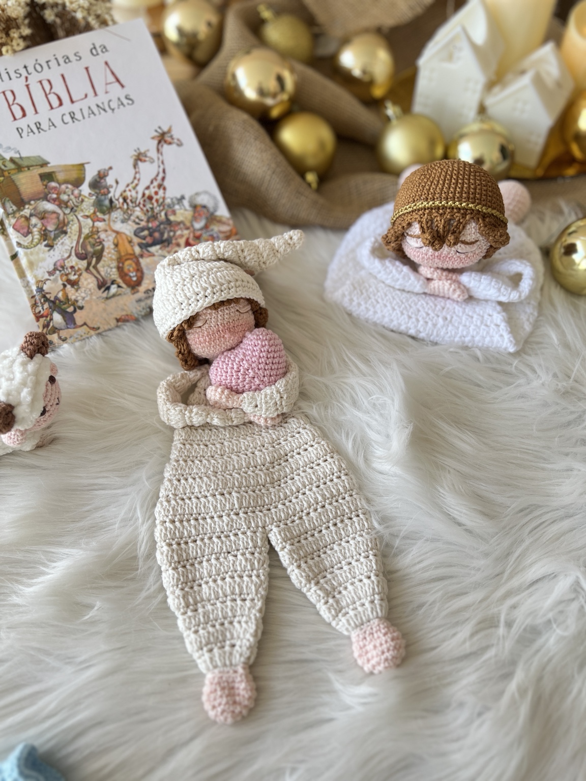 Naninha do Menino Jesus em crochê, com gorro e um coração rosa, em cenário natalino