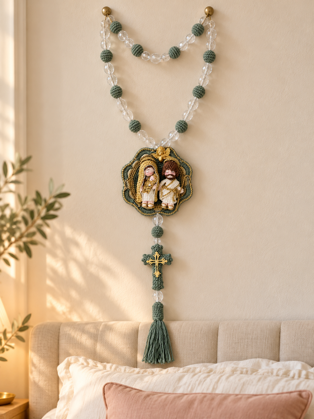 Terço da Sagrada Família em verde e dourado, pendurado na parede acima de uma cama em tons claros